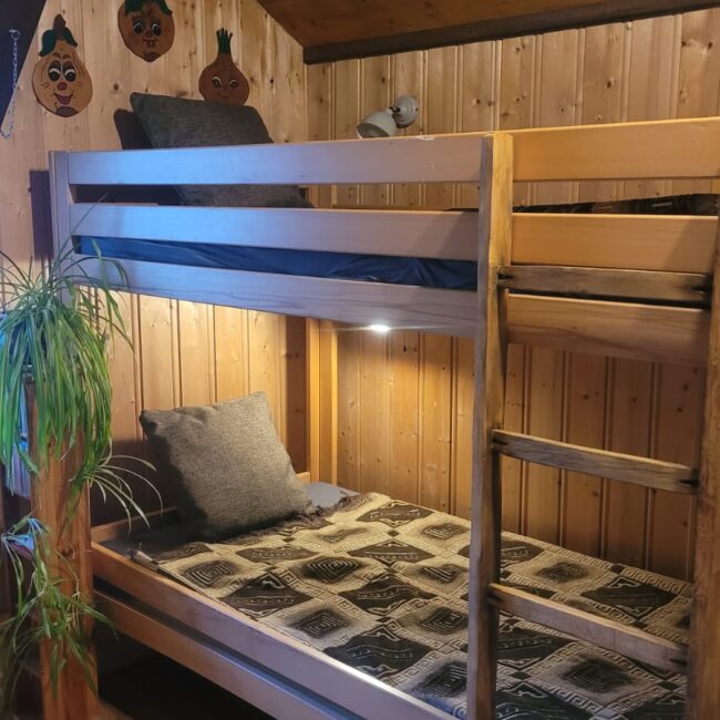 Etagenbett aus Holz mit gemütlicher Bettwäsche und beleuchtung