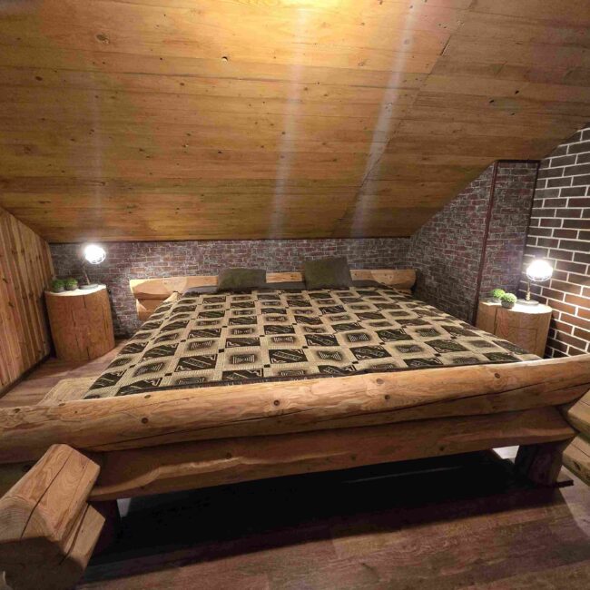 Großes Doppelbett aus rustikalem Holz in einem gemütlich eingerichteten Schlafzimmer